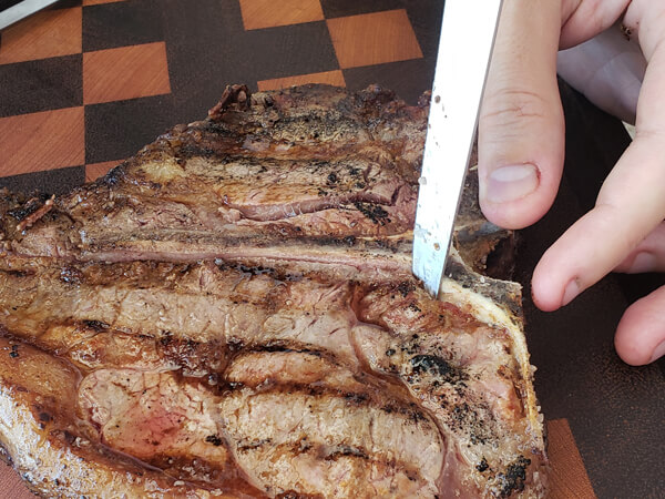 Retirando o osso do T-Bone com faca especial para carne e churrasco